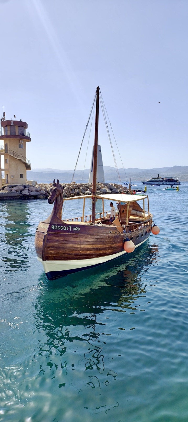 Alissar, Sea Guard's Phoenician-style wooden boat with its carved horse-head bow, moored near Aqaba's lighthouse